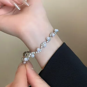 Detailed close-up of a wavy silver bracelet with white pearls and sparkling rhinestones.