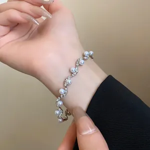 Detail of an irregular silver bracelet with pearls and rhinestones on a woman's wrist