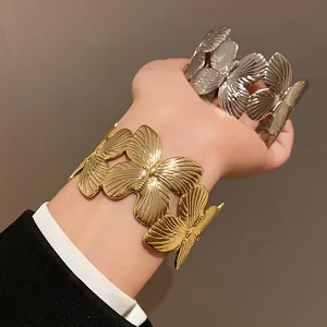 Macro view of gold and silver butterfly wing cuff bracelets showing intricate texture