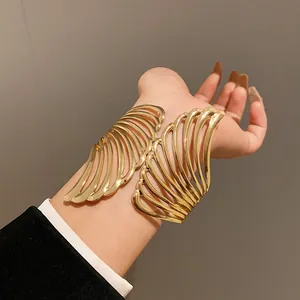 Detailed close-up of gold-finish leaf-shaped open cuff bracelet on model's wrist