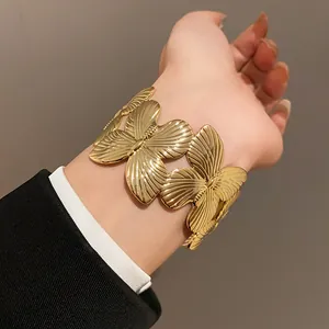 Elegant wide gold butterfly cuff bracelet with textured wings on a stylish female wrist.