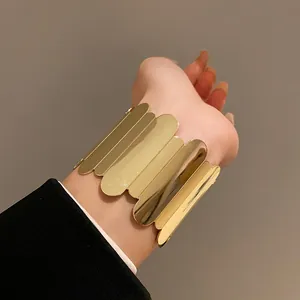 Elegant gold metal open cuff bracelet featuring a unique scalloped petal design worn on wrist