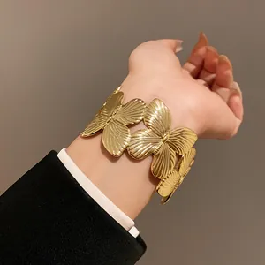 Elegant gold-toned metal butterfly cuff bracelet featured in a close-up lifestyle shot