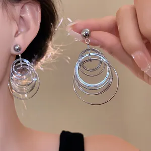 Detailed close-up view of silver geometric multi-ring drop earrings worn by a model