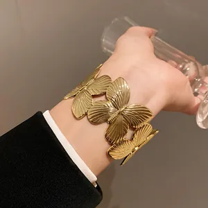 Close-up view of a gold-colored butterfly leaf metal cuff bracelet on a wrist