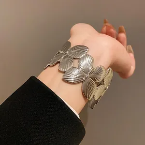 Close-up of a vintage-style metallic butterfly cuff bracelet on a female wrist