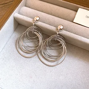 Detailed view of silver multi-layer geometric hoop drop earrings in a jewelry box