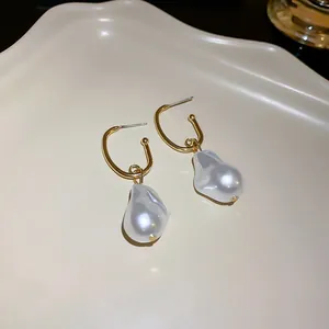 Close-up detail of elegant French-style gold hook earrings with irregular white pearls.