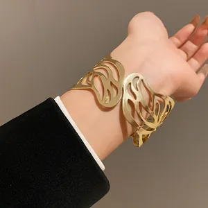 Detailed macro shot of a minimalist gold metal open cuff bracelet with leaf cutout design
