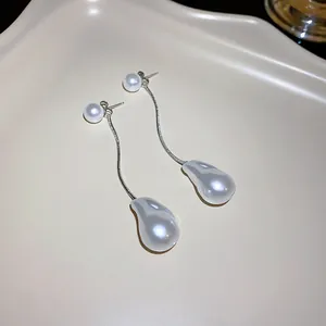 Detailed view of long dangling earrings with irregular pearls and silver snake chains