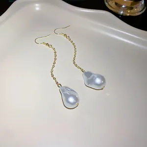 Detailed macro view showing the elegant irregular baroque pearl drop earrings with gold chain.