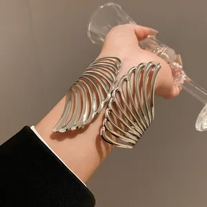 Close-up of stylish silver wing-shaped metal cuff bracelet with hollow leaf design