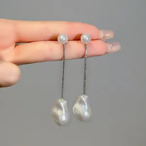 Close-up detail of irregular baroque pearl tassel earrings featuring a silver snake chain.