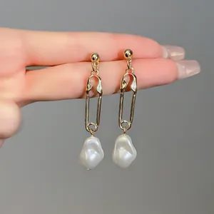 Detailed view of French style gold safety pin earrings with irregular white Baroque pearls