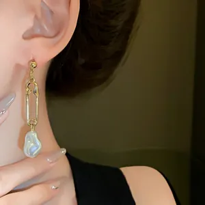 Close-up of French-style gold safety pin earring with irregular baroque pearl