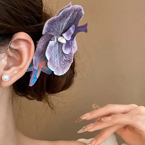 Close-up of a purple fabric orchid hair clip worn on the side of a woman's hair