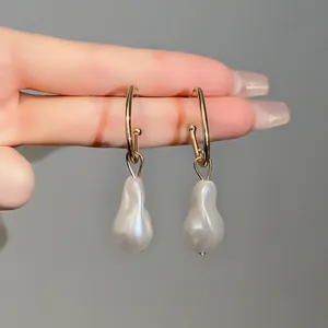 Macro detail of gold hoop earrings featuring elegant white irregular baroque pearls