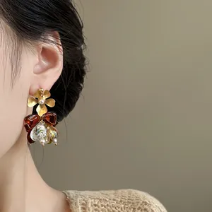 Close-up of vintage Maillard style flower and bow drop earrings on an Asian model's ear