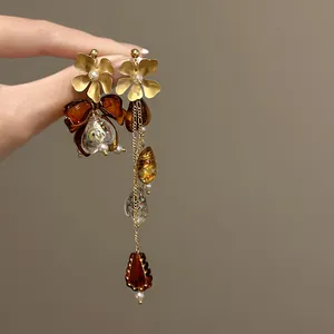 Detailed macro view of asymmetric Maillard-style flower and bow earrings with amber beads
