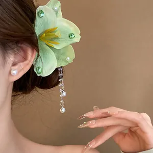 Detailed side view of elegant light green fabric flower hair clip with pearl tassels