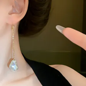 Close-up detail of elegant baroque pearl tassel dangling earrings with a fine gold chain.