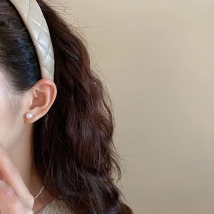 Detail view of a quilted beige leather headband on a model's head showing vintage style.