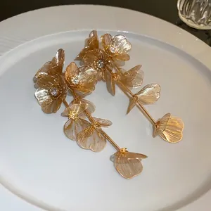 Elegant long gold flower tassel earrings with sparkling diamond accents on a white plate