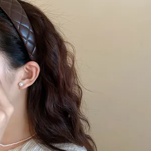 Detail shot of a brown quilted leather headband with an elegant small pearl stud earring.