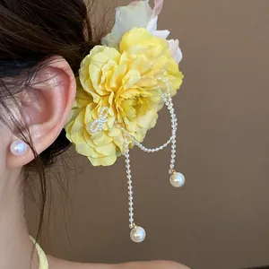 Close-up detail of a yellow floral hair clip with elegant dangling pearl tassels