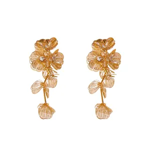 Elegant gold floral tassel earrings with sparkling rhinestones on white background
