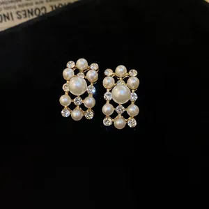 Detail view of vintage style geometric pearl and crystal earrings on black velvet.