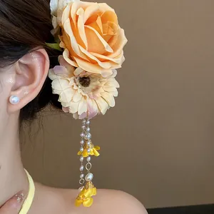 Macro detail of fabric flower hair clip featuring elegant pearls and yellow tassels