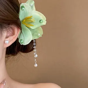 Side view of mint green fabric flower hair clip with elegant dangling pearl tassels.