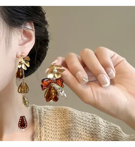 Close-up of asymmetric flower and bow earrings in a vintage amber Maillard style