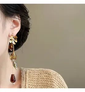 Detail shot of vintage asymmetric long flower drop earrings in warm amber tones