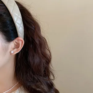 Detailed view of a beige quilted padded leather headband for a high cranial look