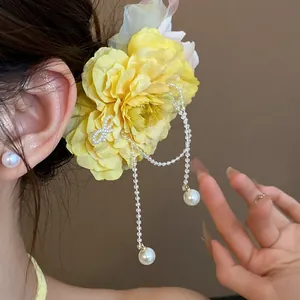 Close-up detail of sweet yellow fabric flower hair clip with elegant hanging pearl tassels