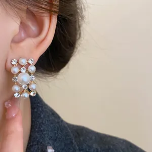 Close-up of elegant French vintage pearl and rhinestone geometric earrings on ear