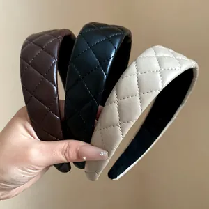 Close-up detail of three stylish quilted leather headbands in black, brown, and cream colors.