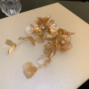 Close-up of elegant gold wire mesh flower earrings with sparkling rhinestone centers.
