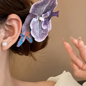 Close-up detail of a purple fabric orchid hair clip with a starfish accent on model's hair