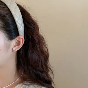 Side detail view of a beige quilted leather headband featuring a retro high top design on model