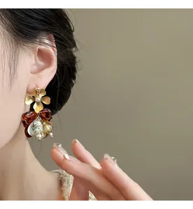 Close-up of vintage-style asymmetric gold flower and brown bow earrings on model