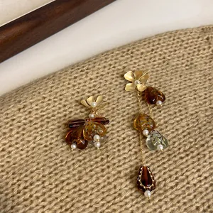 Macro view of asymmetrical vintage earrings featuring amber heart charms and gold flower studs