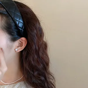 Detail view of a vintage-style black quilted leather headband worn by a woman.