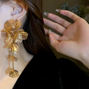 Close-up of oversized gold flower tassel earrings on a model with sparkling stones