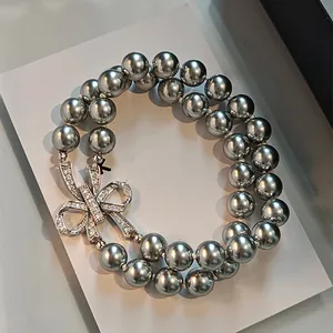 Detailed macro shot of a double-strand grey pearl bracelet with a sparkling crystal bow.