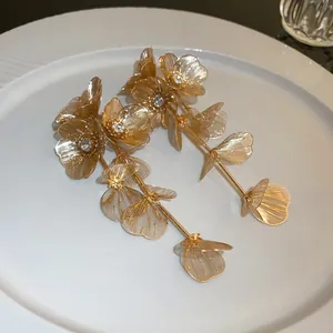 Close-up of gold mesh flower tassel earrings featuring sparkling rhinestone centers