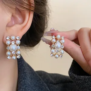Vintage-style rectangular earrings with pearls and rhinestones shown on ear and hand.
