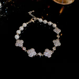 Detail view of pearl bracelet with sparkling four-leaf clover motifs on black background